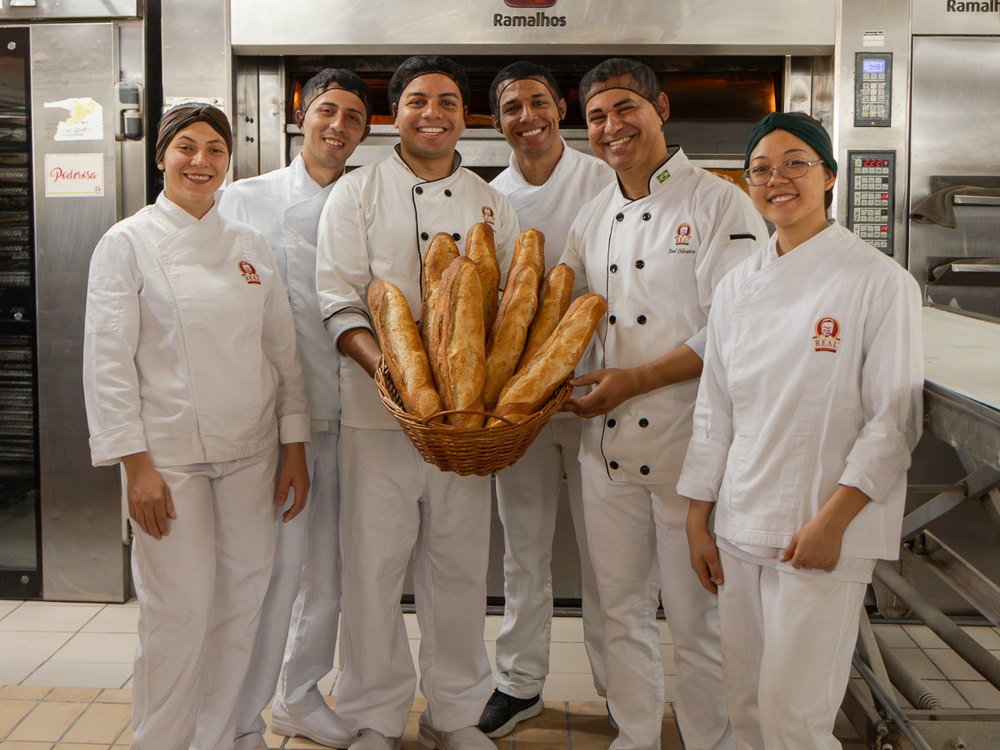 Equipe de padeiros segurando uma cesta de pães
