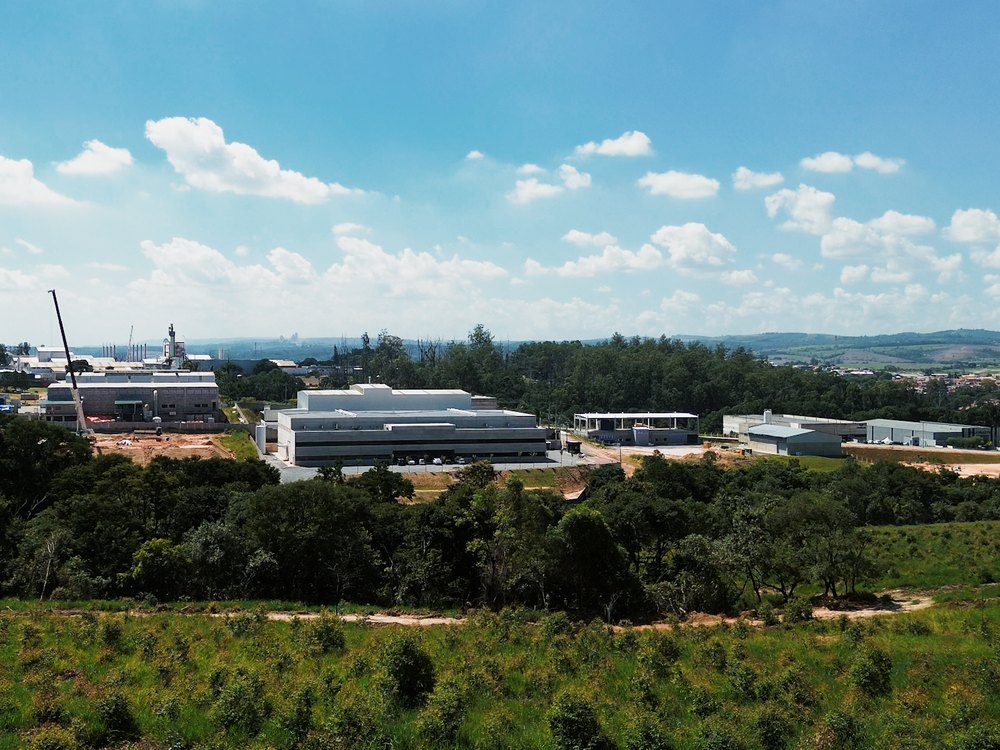 Vista aérea de complexo industrial cercado por mata